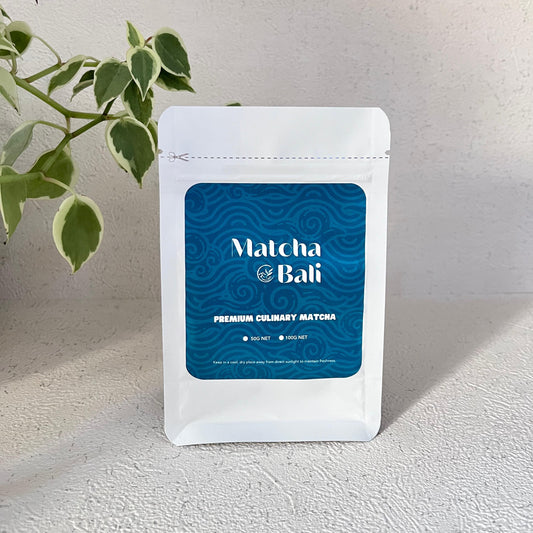 White package of Matcha Bali with blue label on a light surface with a plant in the corner.